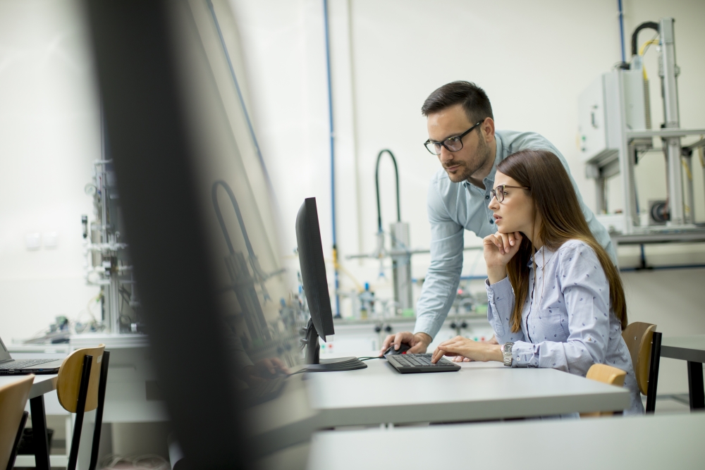 Side view of focused students using desktop pc in classroom