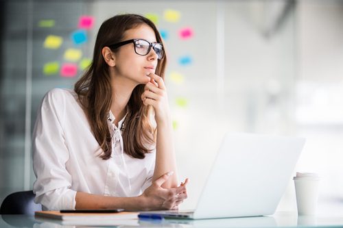 successful businesswoman working on laptop computer and thinks on new ideas in her office dressed up in white clothes