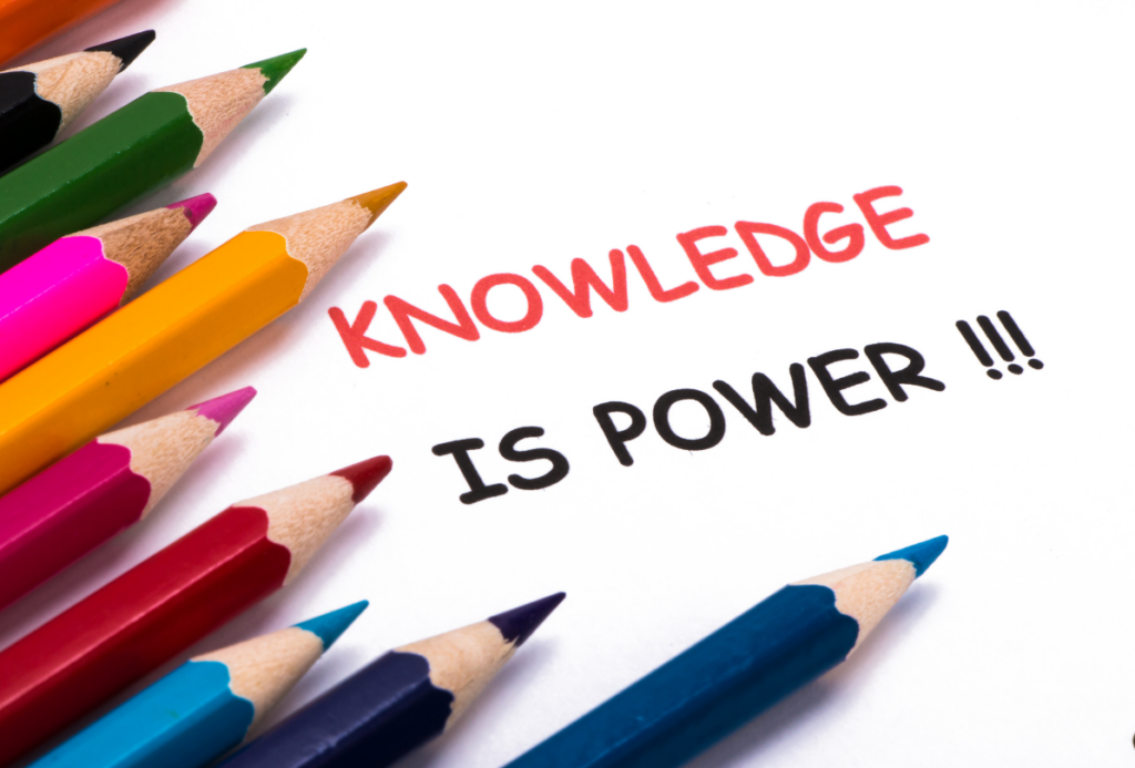 Na białym tle leżą kolorowe kredki. Obok napis "Wiedza to siła" po angielsku.