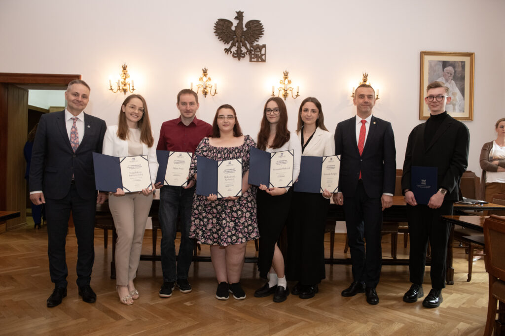 Wspólne zdjęcie laureatów z WIiTCh z rektorem i prorektorem. Nagrodzeni trzymają w rękach otwarte dyplomy